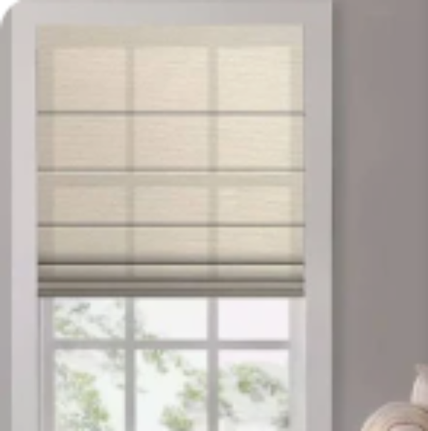 A beige roller shade with horizontal slats, shown partially drawn up on a window with a white frame, set against a neutral gray wall.